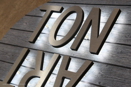 Butlerfinish-Leuchtbuchstaben auf einem bedruckten Holzschild.