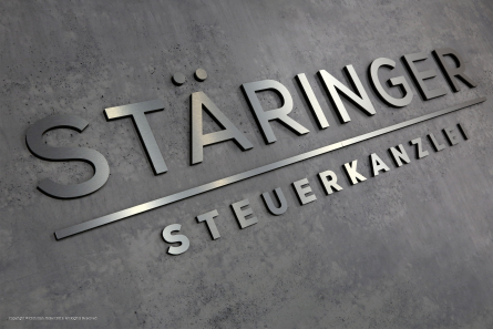 Buchstaben in Edelstahl-Optik mit schwarzem PVC hinterlegt.