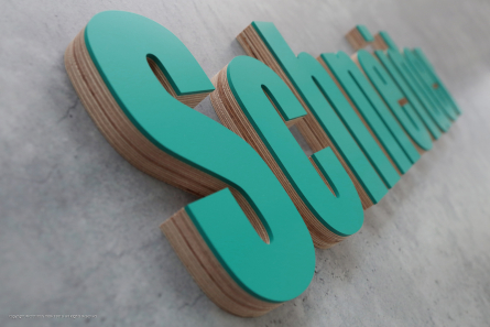 3D-Holzbuchstaben aus Multiplex mit einer Front aus lackiertem Acrylglas.