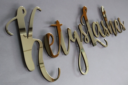 Goldenes Logo in Spiegeloptik mit Gewindestiften montiert.