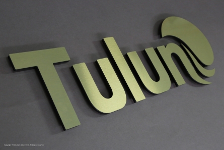 Dibond-Butlerfinish-Gold, hinterlegt mit schwarzem Acrylglas als 3D-Logo.